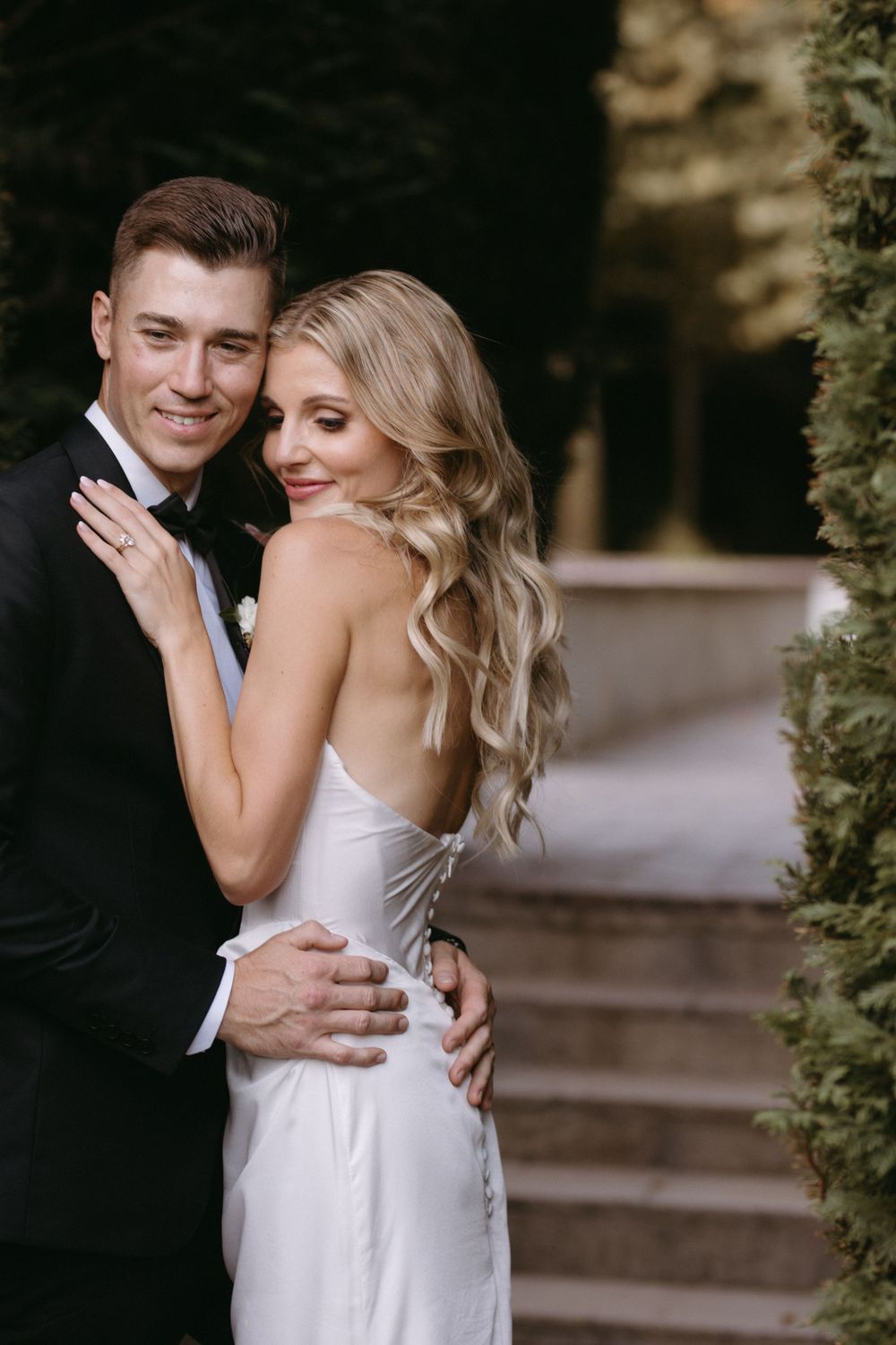 A couple shares an intimate moment under a vine-covered arch.