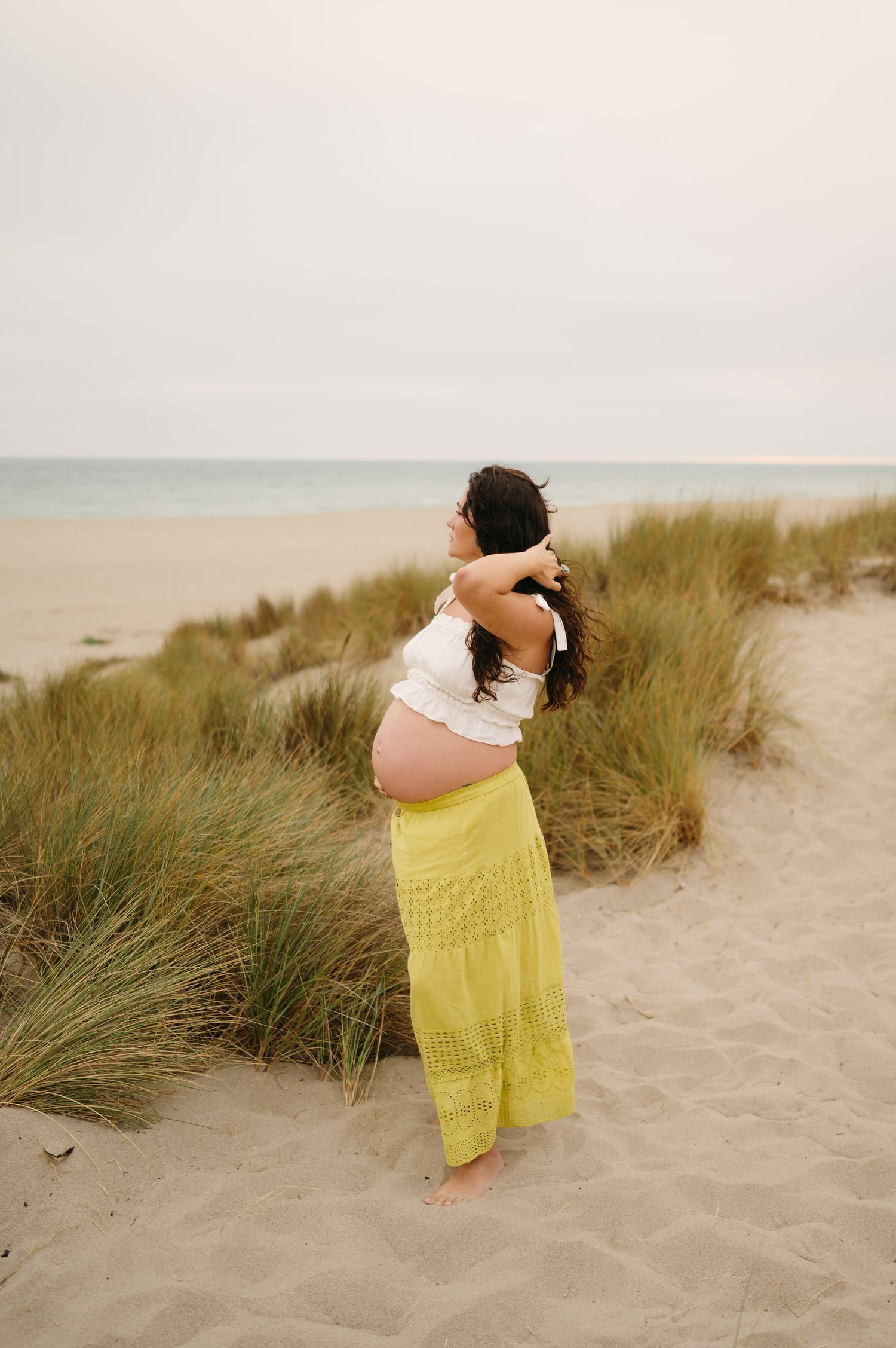 woman in skirt and boho top poses on sand dunes during her Mandalay beach photoshoot by Ventura maternity Photographer