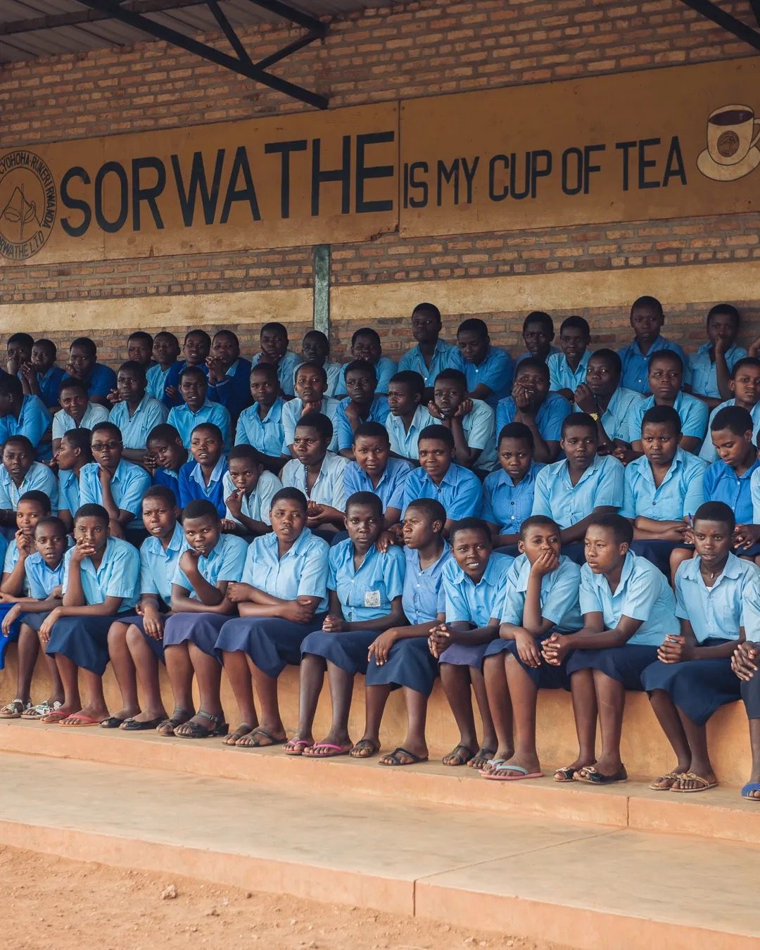 Students sit together in uniform during a school programme focused on education, wellbeing and community support