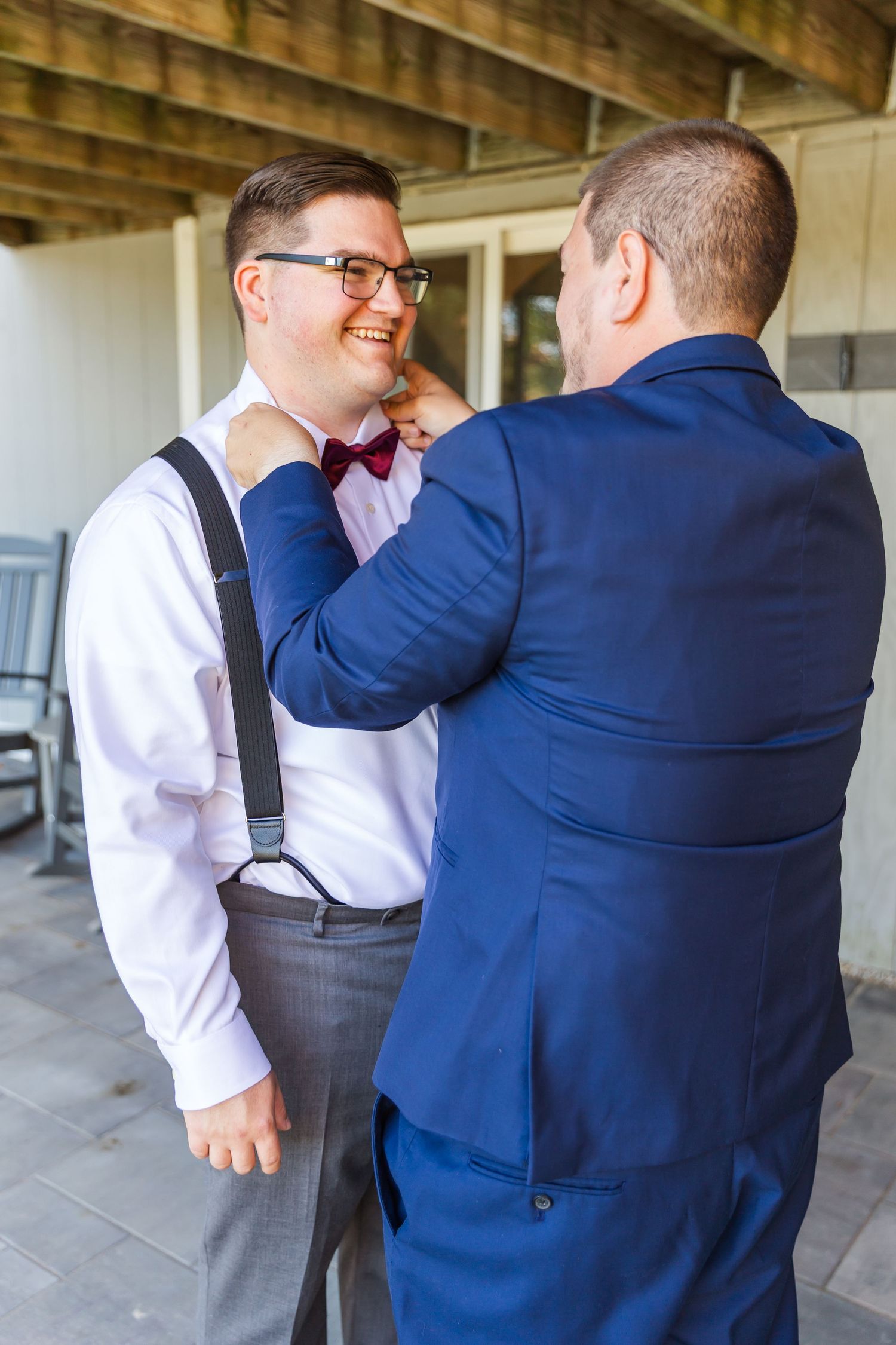 Two people in formal attire share a friendly moment in a covered outdoor setting.