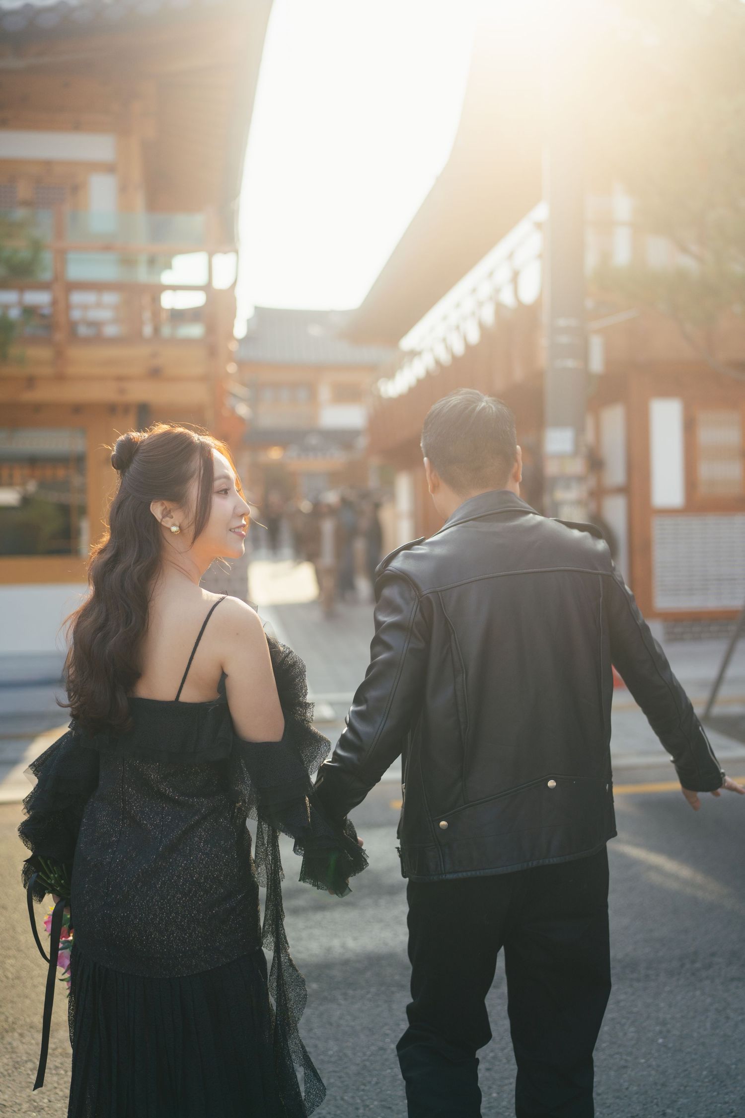 Couple walking away from camera in matching black outfits during golden hour sunset.