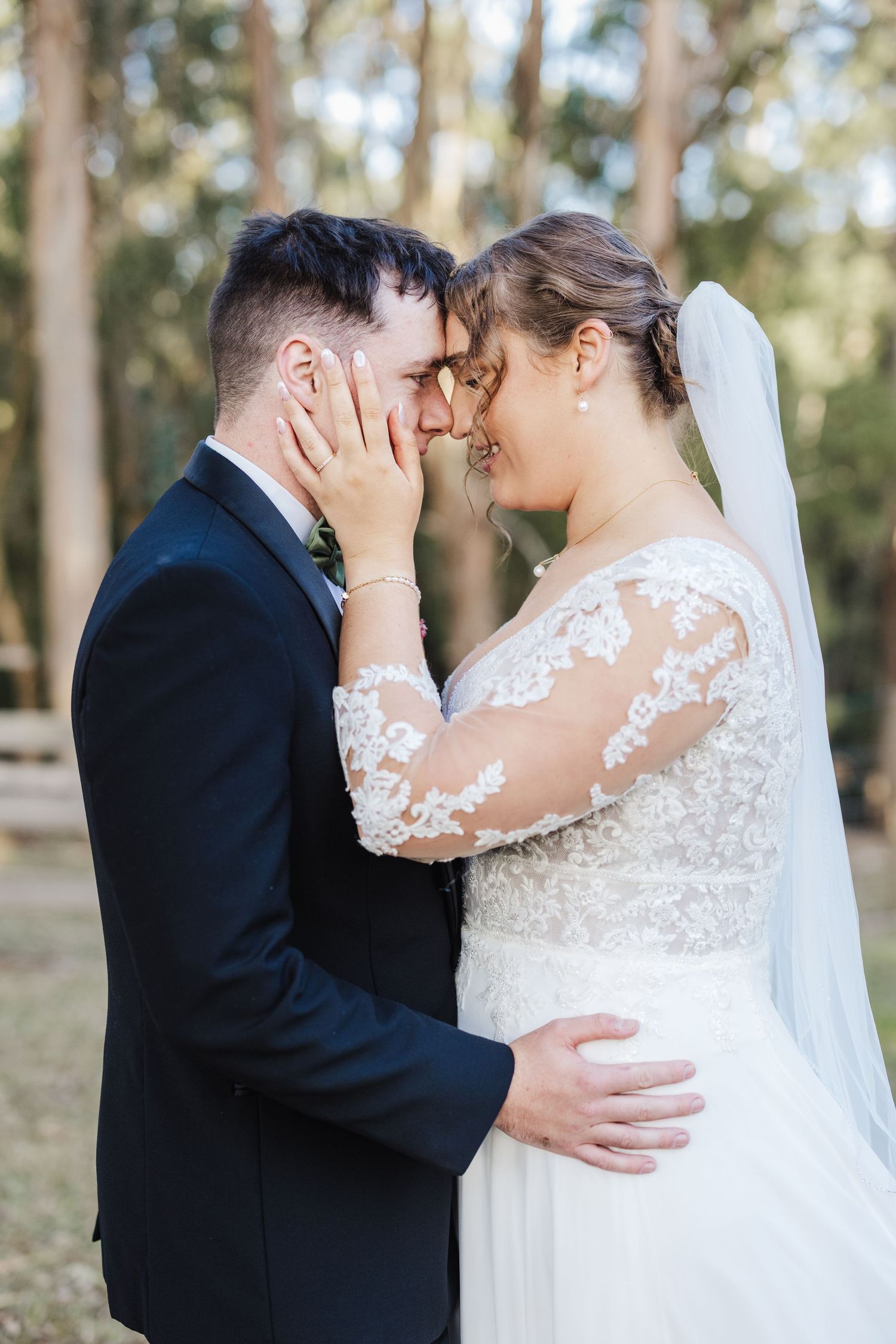 Intimate wedding portraits showing tender moments between newlyweds in a sunlit forest setting.