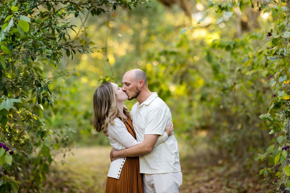 A couple shares intimate moments in a lush garden setting during an outdoor photo session.