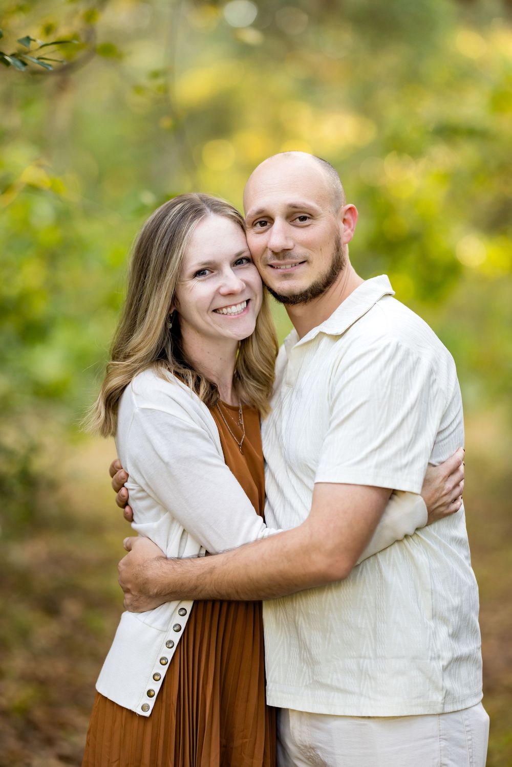 A couple embraces outdoors in a romantic autumn setting with golden bokeh and natural lighting.
