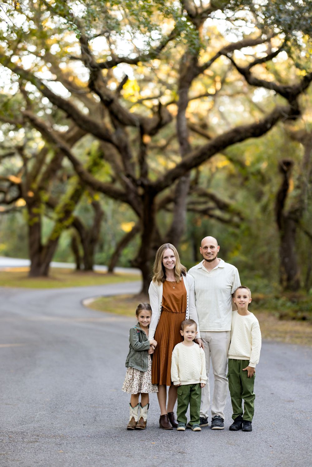 A family walking together on a winding tree-lined path during golden hour at a park.