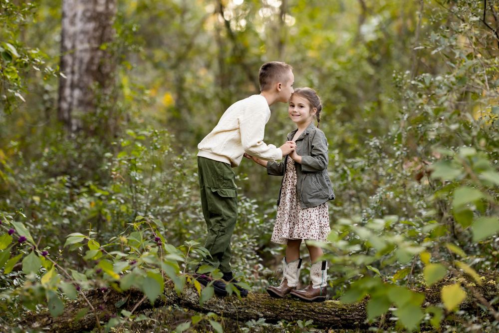 A couple poses for romantic engagement photos in a lush green forest setting during autumn.