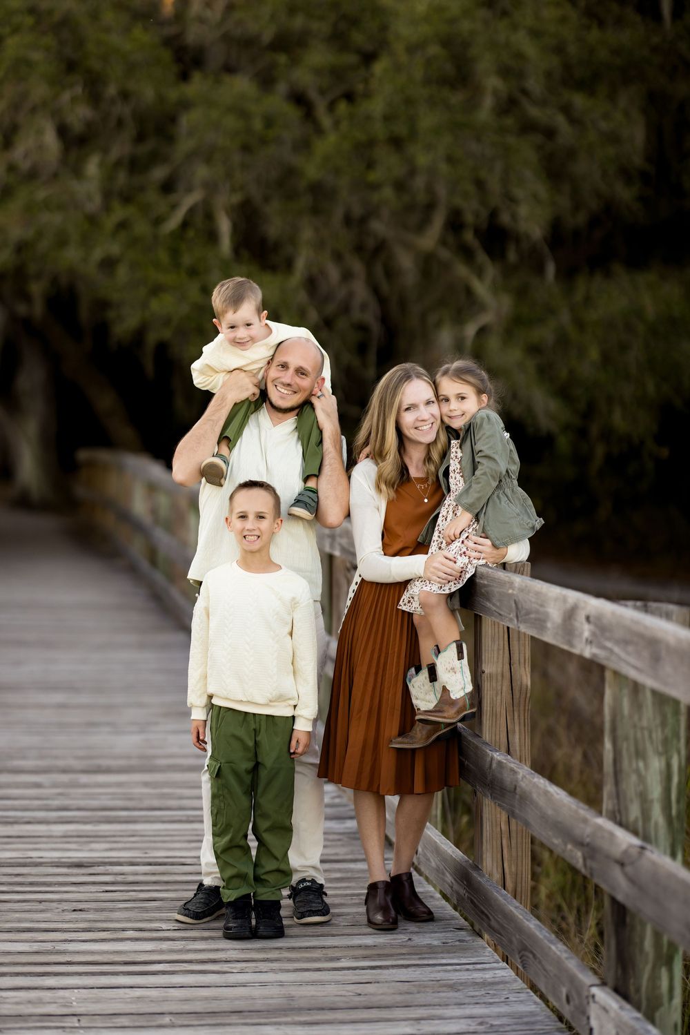 Children walk along a wooden boardwalk path through natural scenery during a family photo session.