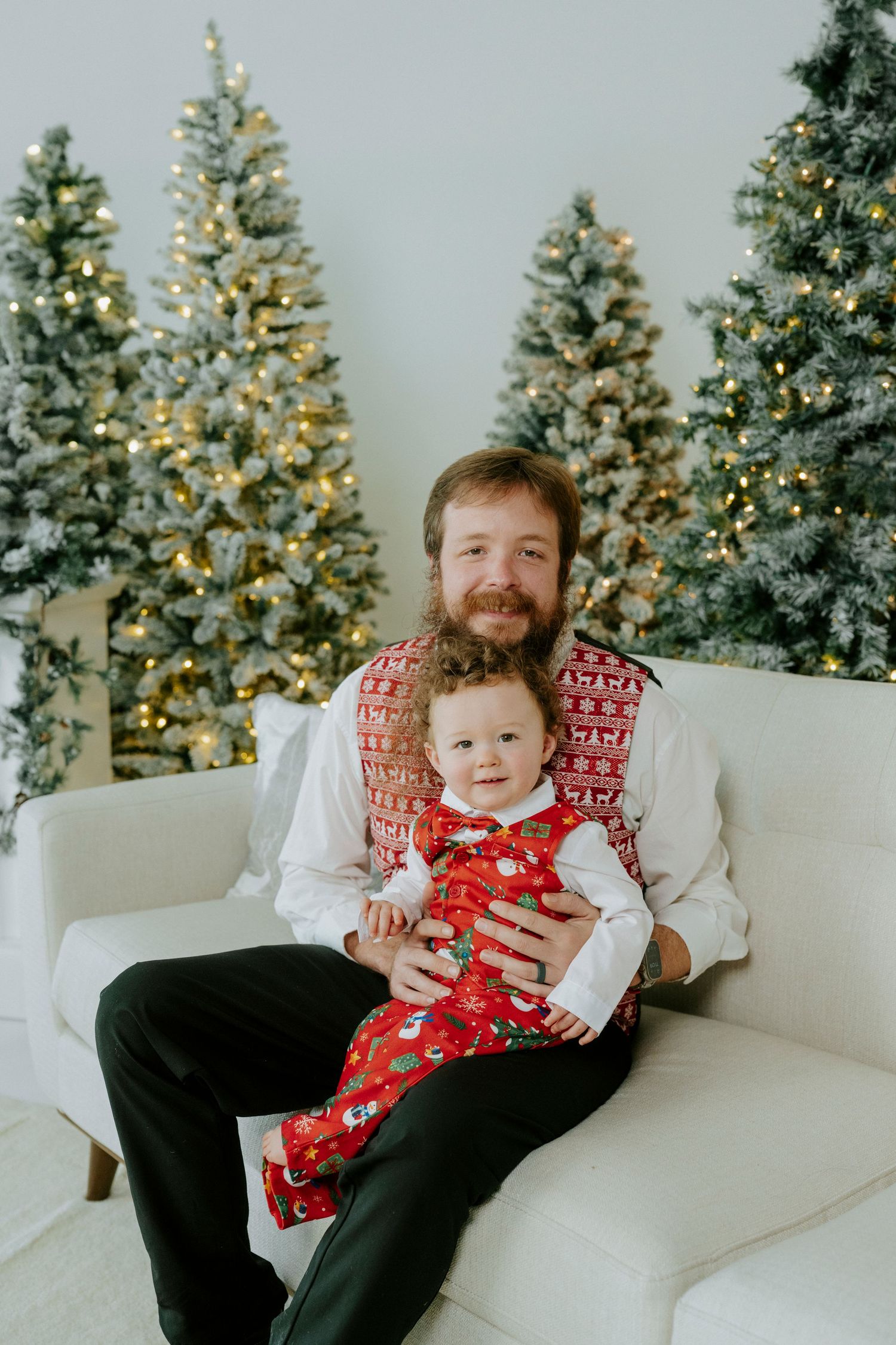 A festive holiday scene with lit Christmas trees in the background and a white couch in the foreground.