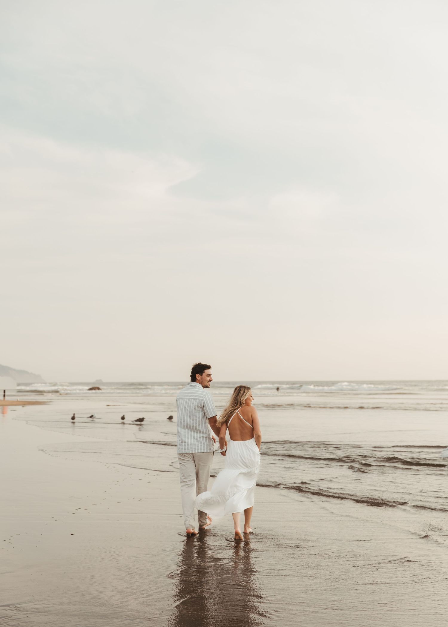 A couple embraces in a golden sunlit field during sunset, creating a romantic silhouette against the natural landscape.
