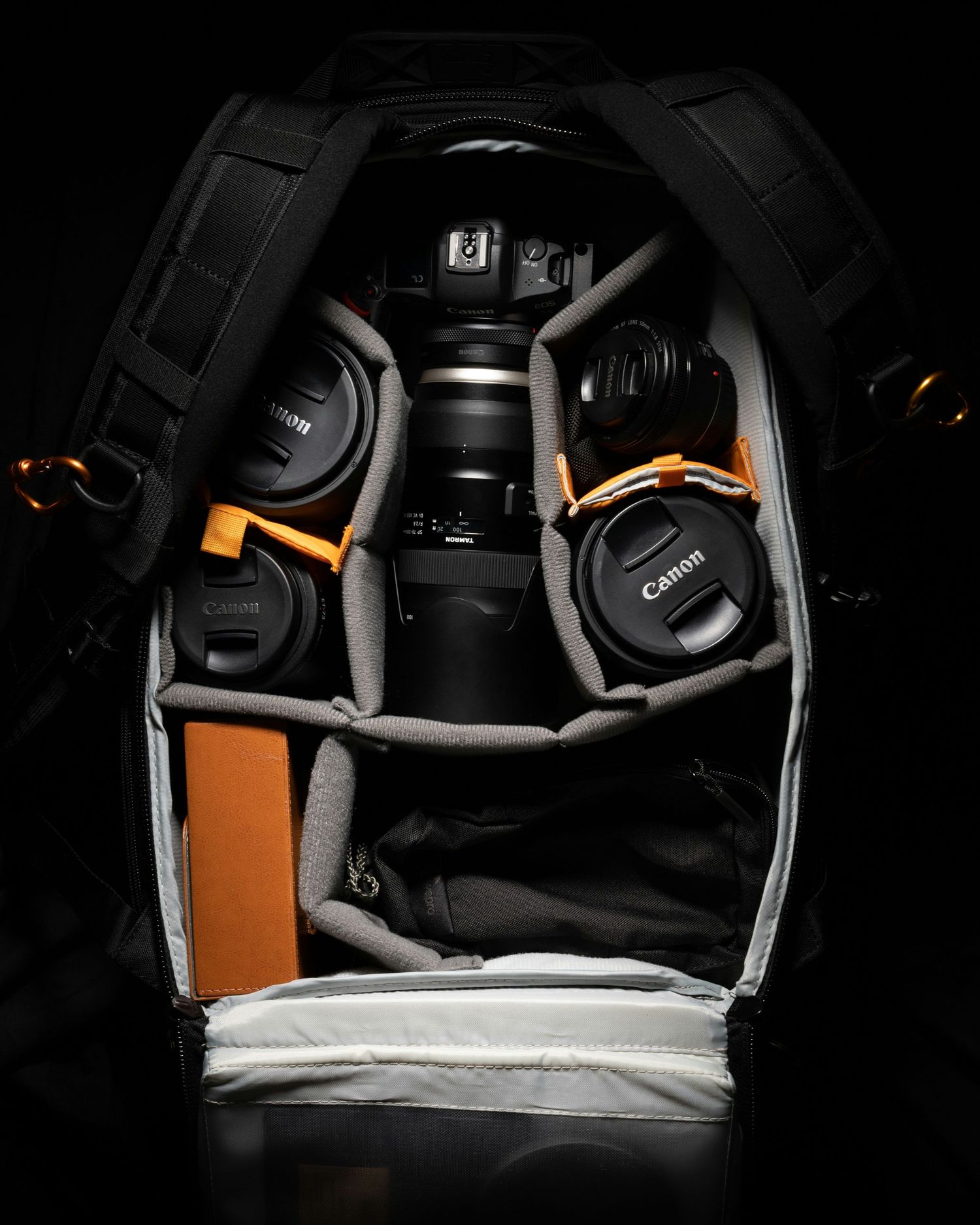 Overhead view of camera equipment and accessories neatly organized in a dark camera bag compartment.