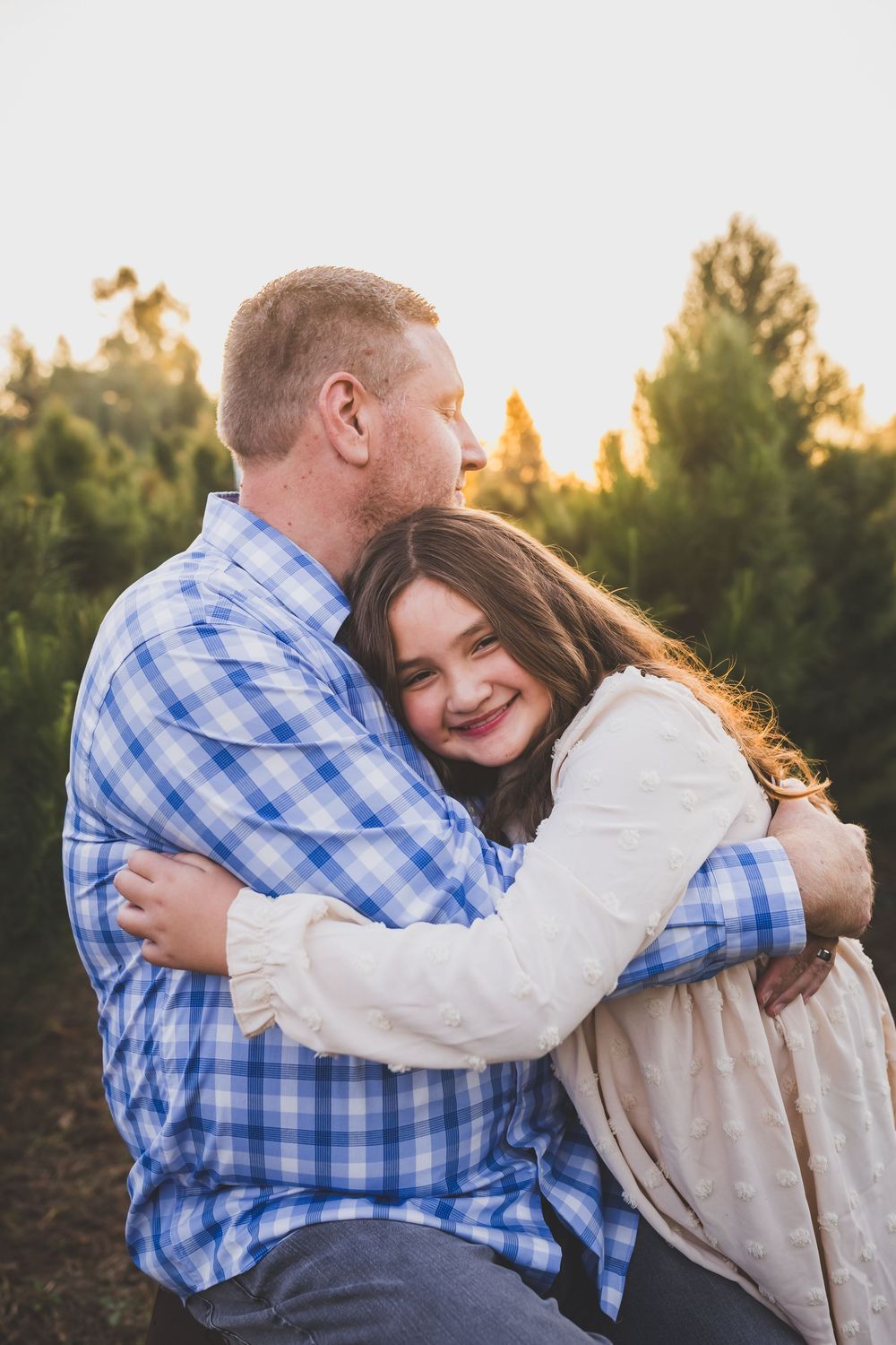 A loving embrace captured during golden hour with trees in the background.