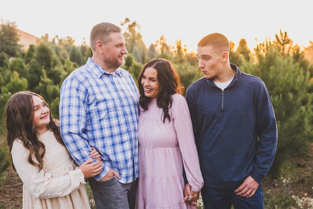 A family enjoys a warm sunset photoshoot among desert plants and trees.