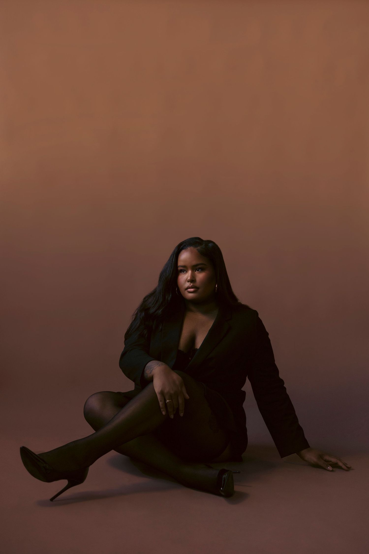 A figure in a black outfit poses gracefully on the floor in a series of artistic silhouette shots against a dark backdrop.