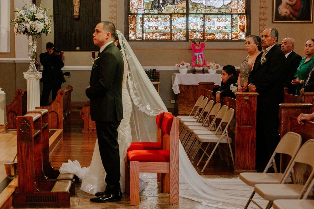 Beautiful church wedding ceremony with stained glass windows and floral decorations along the aisle.