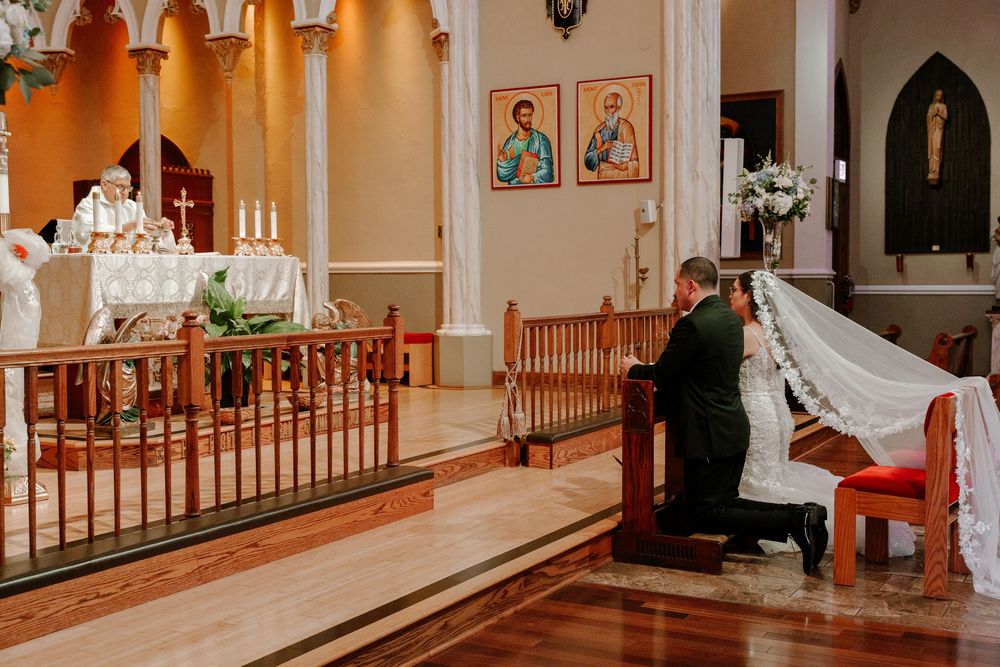 Interior of a Catholic church with ornate architecture and religious artwork during a wedding ceremony.