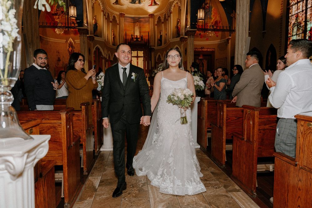 Wedding ceremony in progress inside a traditional church with wooden pews and elegant lighting.