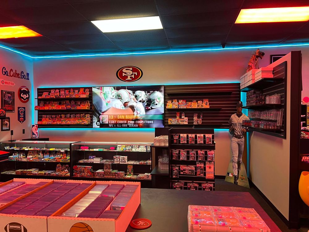 Retro gaming store interior with SF 49ers logo and merchandise displays illuminated by red and blue lighting.