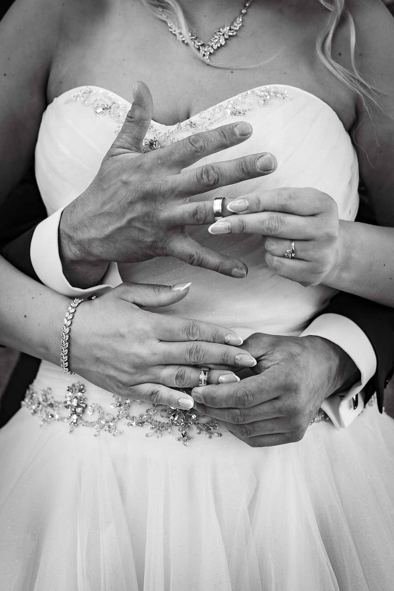 Black and white detail shots of hands and wedding rings against a white dress.