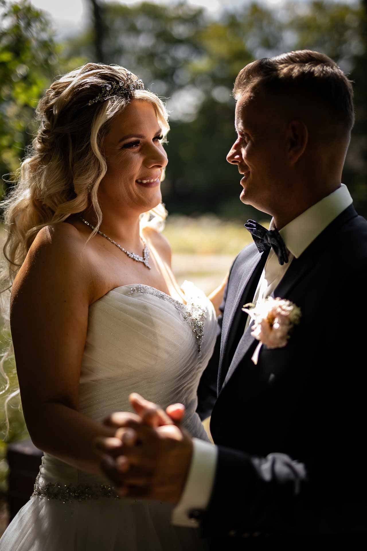 Romantic wedding couple shares intimate moments in natural sunlight during outdoor photo session.