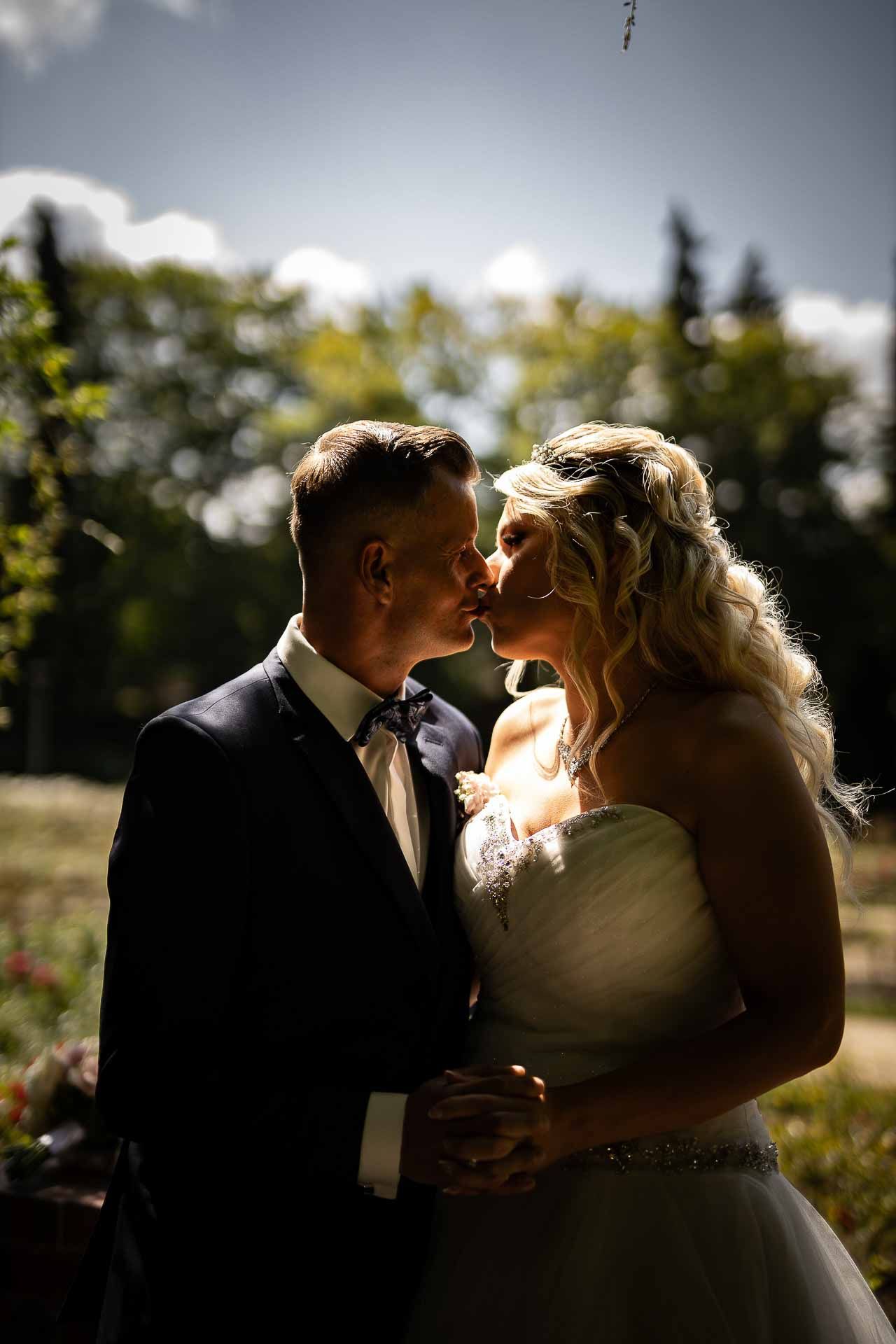 Newlyweds share tender moments in golden afternoon light during outdoor photography session.