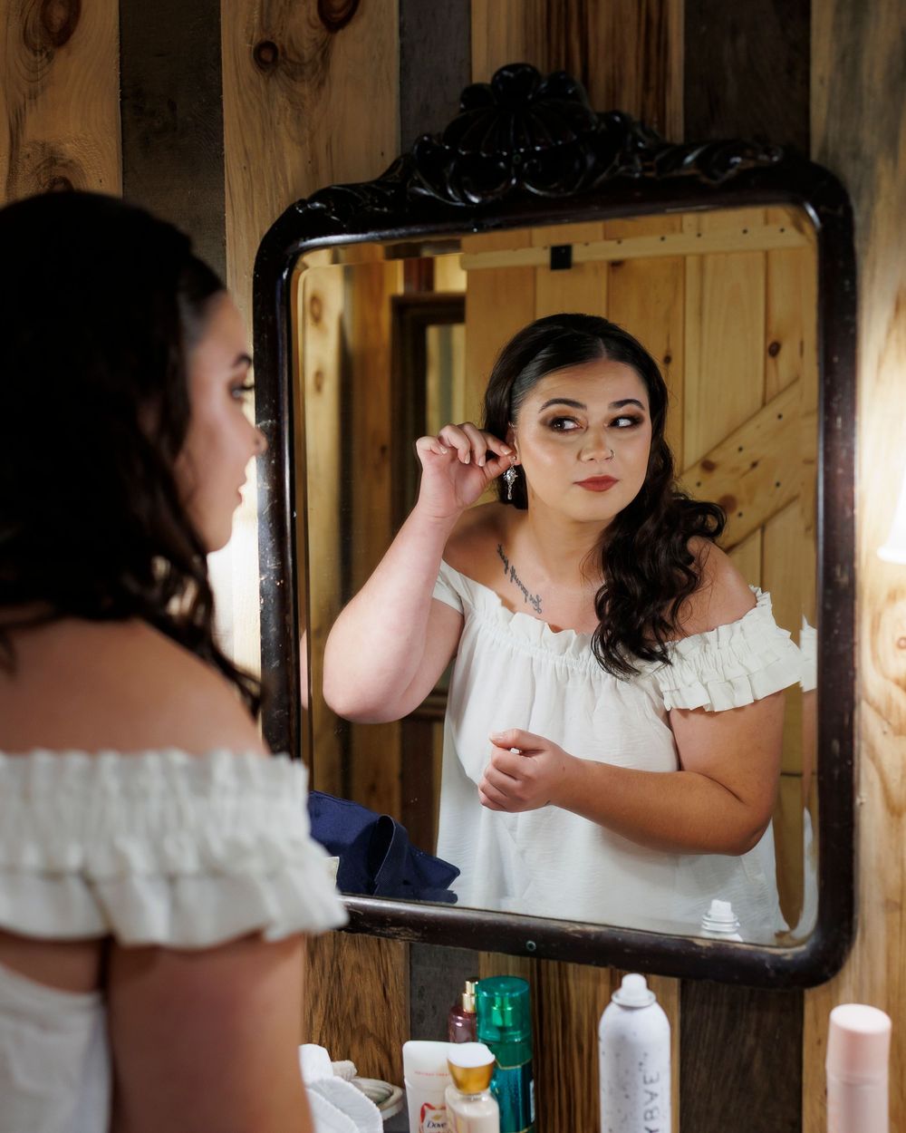 Wedding preparation scene with vintage mirror and rustic wood paneling in a barn setting.