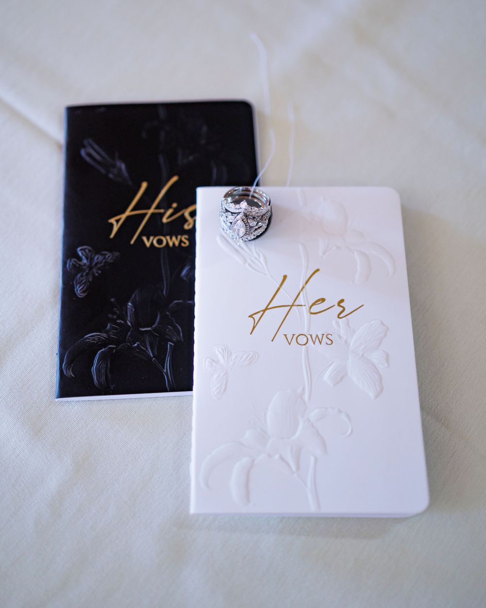 Black and white wedding vow books with elegant gold lettering displayed on a light surface.