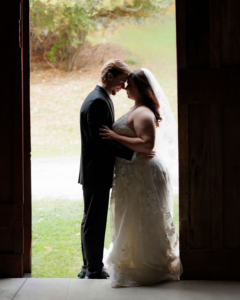 Silhouetted couple shares an intimate moment in a barn doorway during their wedding.