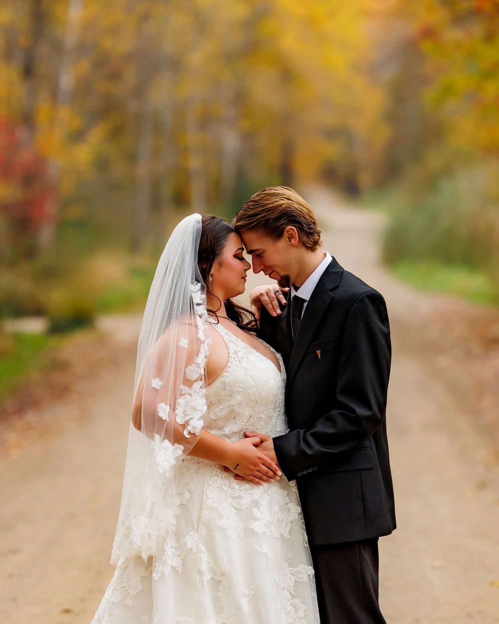 Autumn wedding scene with golden foliage creating a romantic backdrop along a country path.