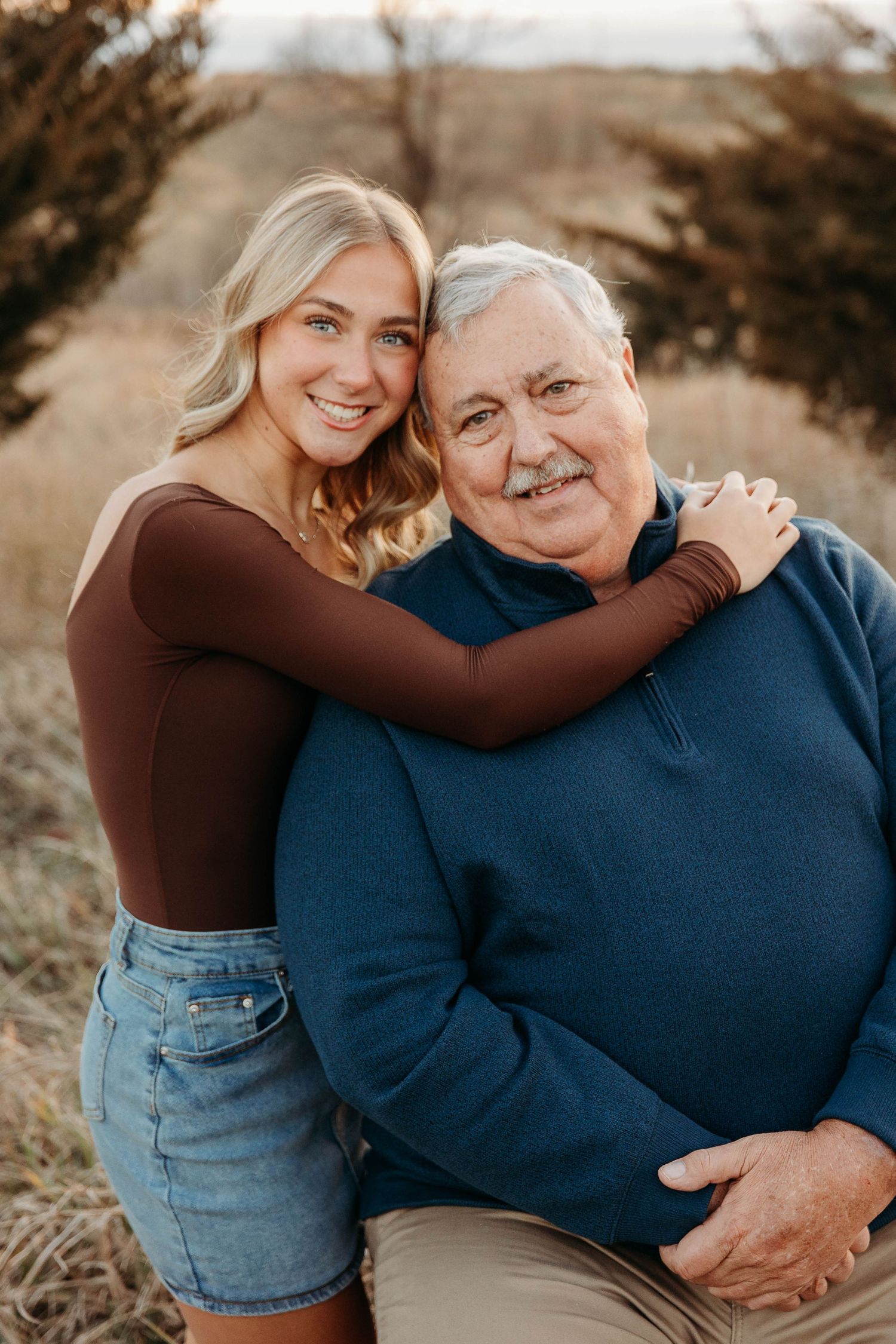 A heartwarming outdoor photo series showing a young woman in a brown top embracing an elderly person in blue.