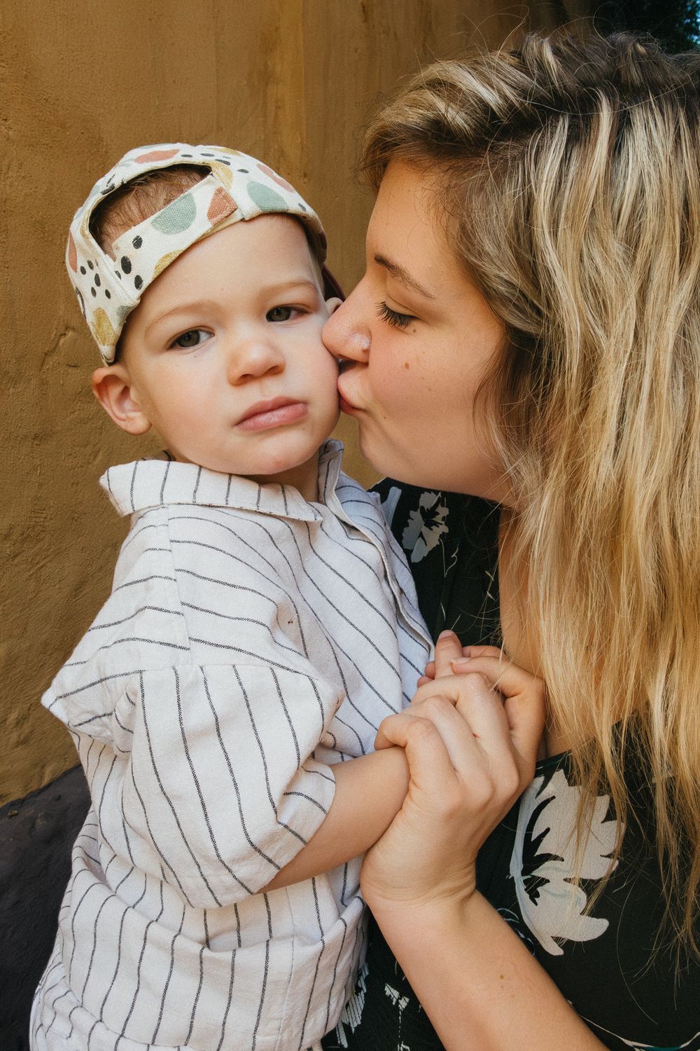 A series of tender moments between a parent and young child wearing a striped shirt against a brown background.