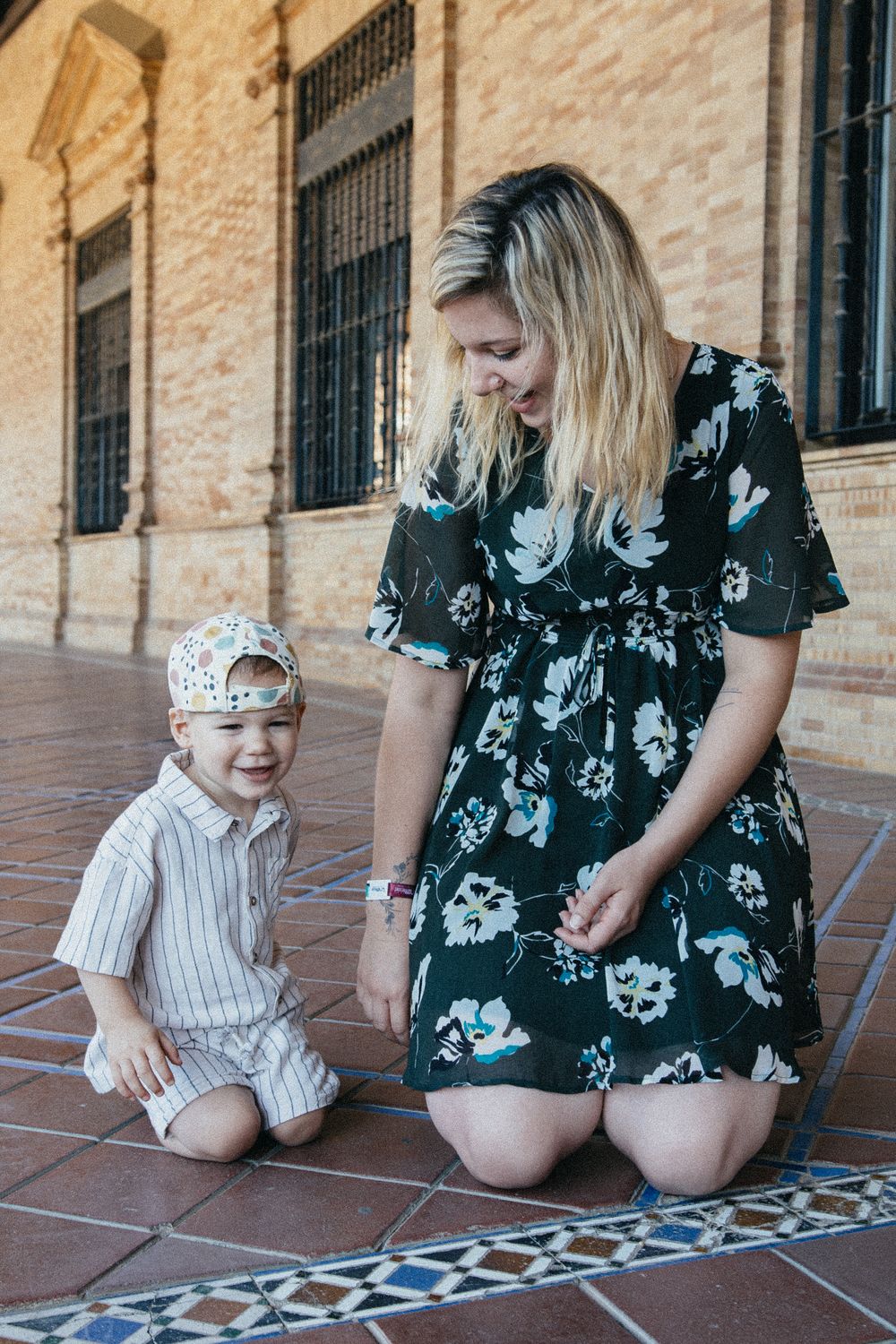 A mother and child sit together on tiled floor playing with chalk, shown in a series of candid moments.