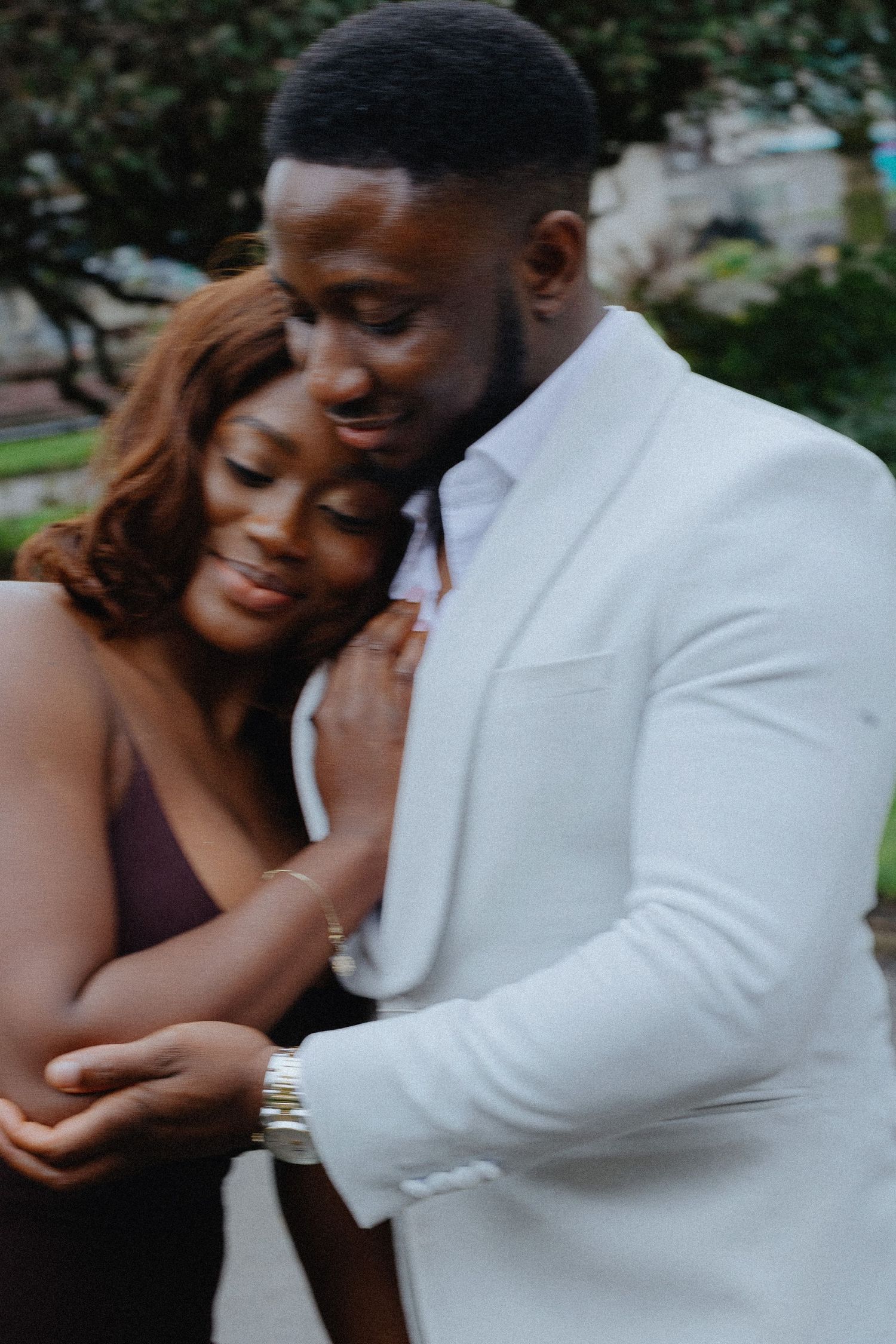 A couple in formal attire share an intimate moment during an outdoor photoshoot.