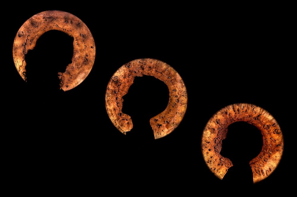 Three rusty antique horseshoes arranged in a row against a black background show their weathered, oxidized surfaces.