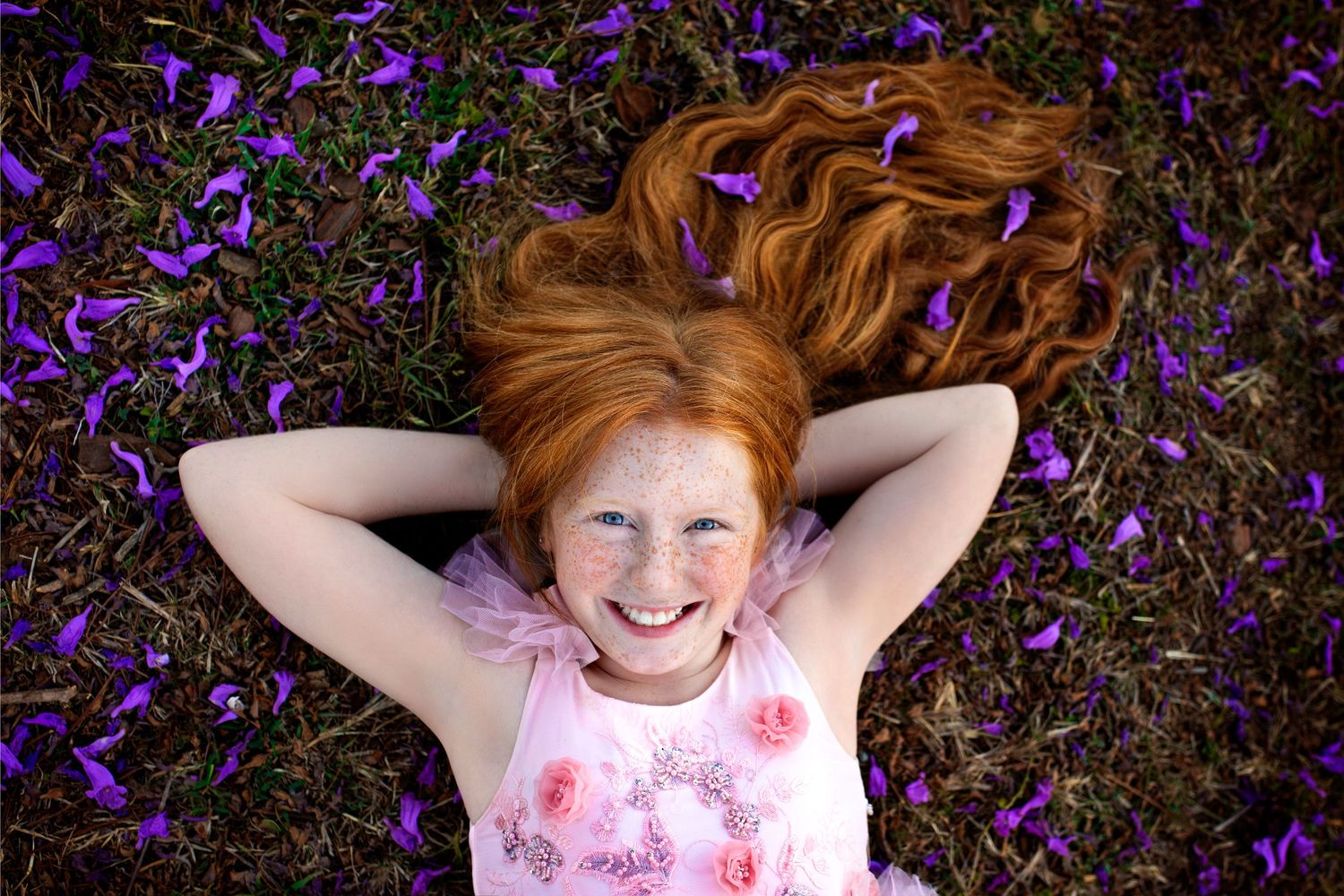 A sequence of photos showing a child in a pink dress lying in a field of purple wildflowers making different playful expressions.