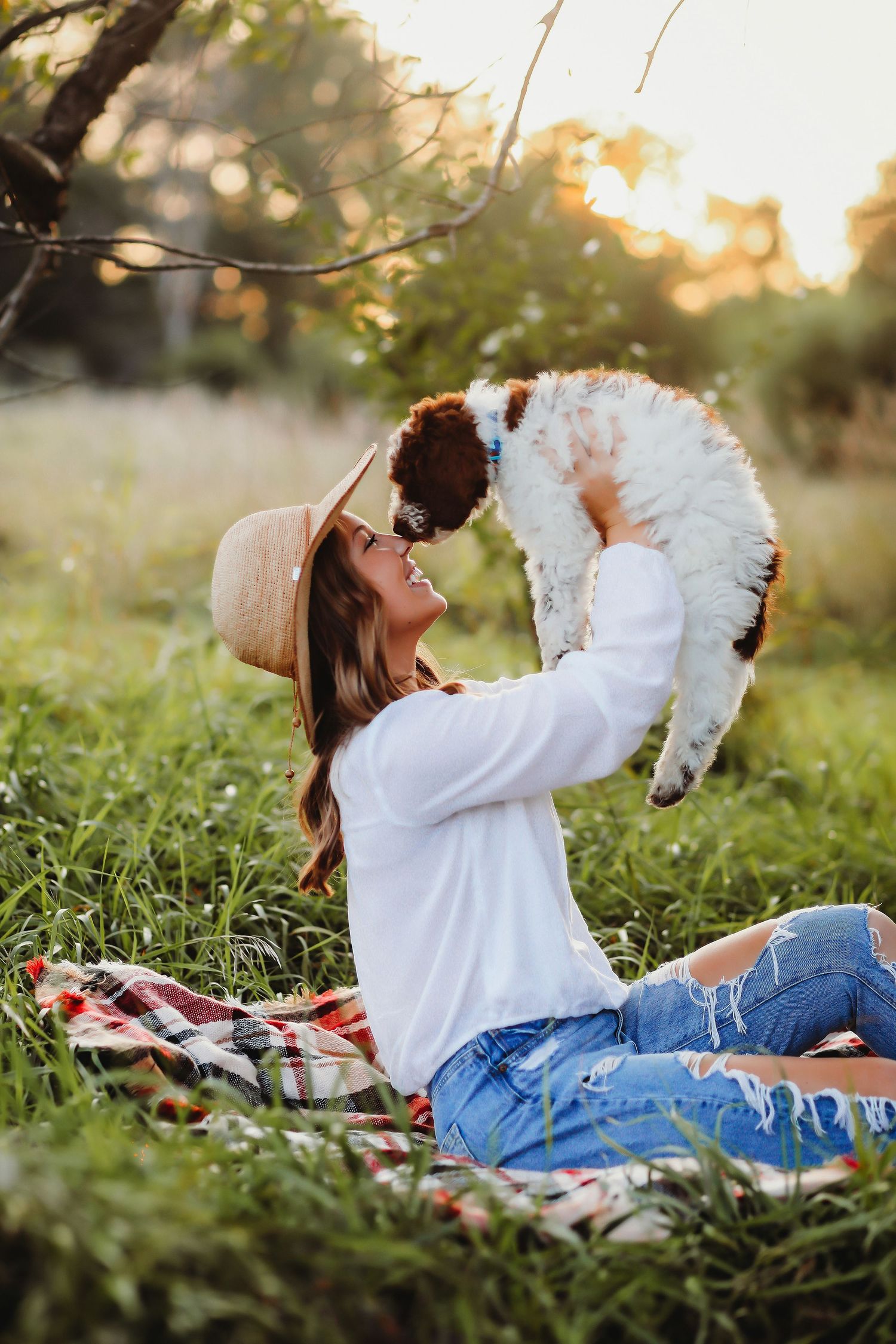 Someone in a hat and white shirt lifting a small dog while sitting on a picnic blanket at sunset.

Best photographer in Illinois