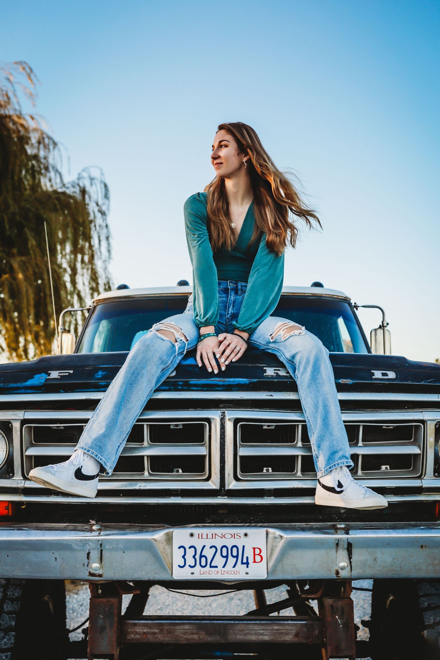 Person in teal sweater sitting on hood of vintage Ford truck with ripped jeans.
Best teen photographer in Illinois