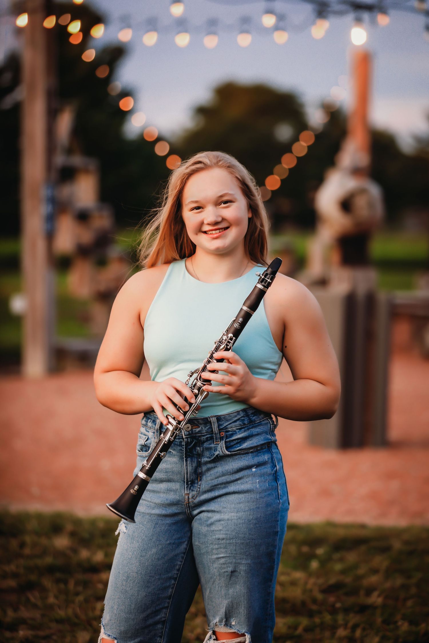 Student musician holds clarinet outdoors at dusk with string lights in background.
Best photographer in Illinois