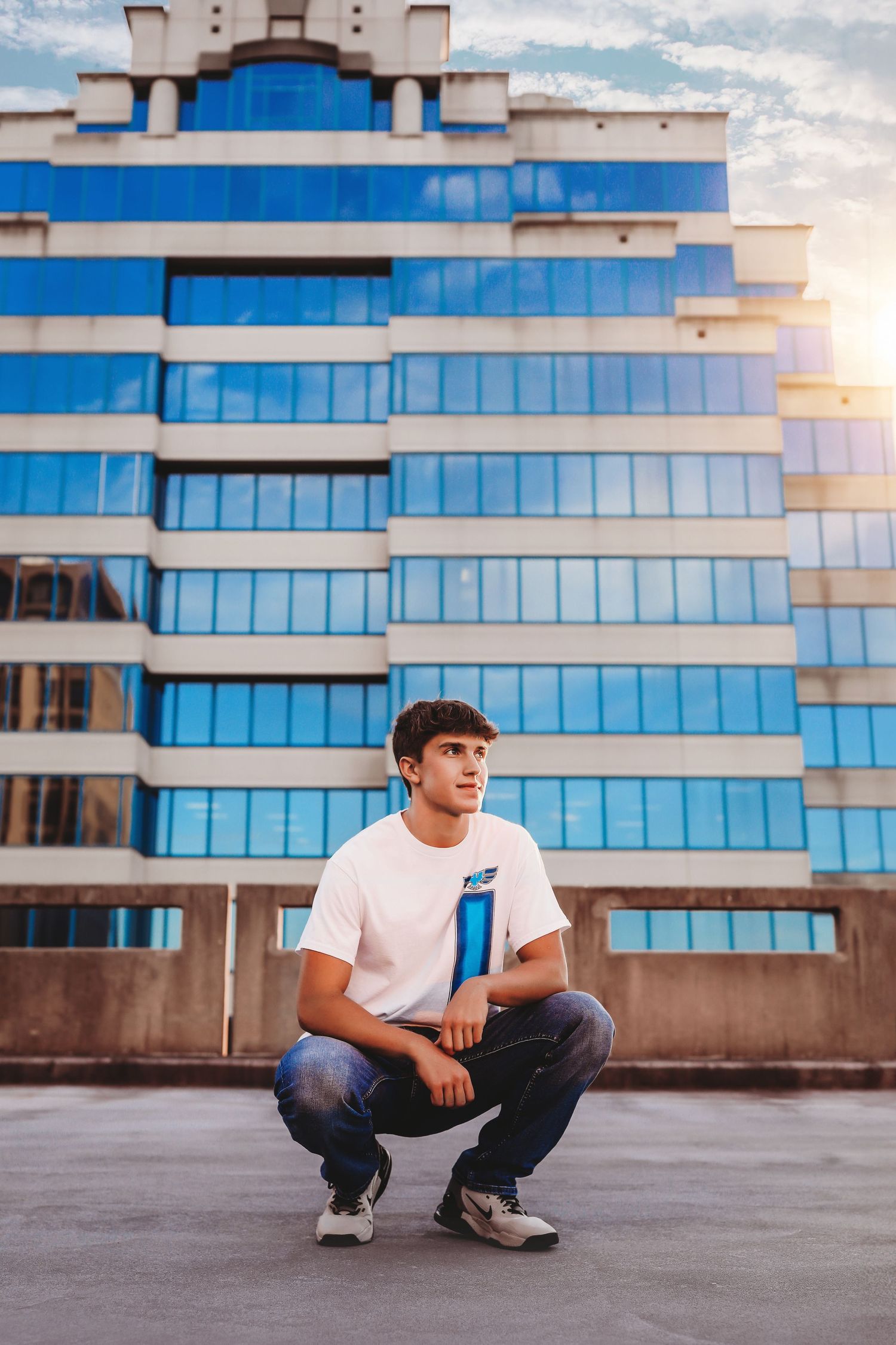 Person in white t-shirt crouching in front of modern glass office building at sunset.
Best photographer in Illinois