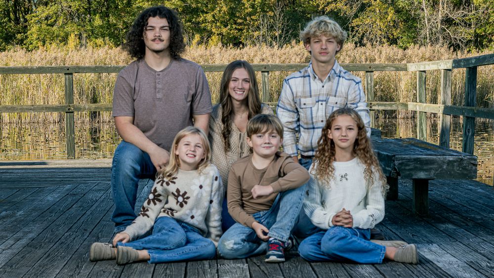 Family members arranged in casual poses on outdoor wooden deck.
