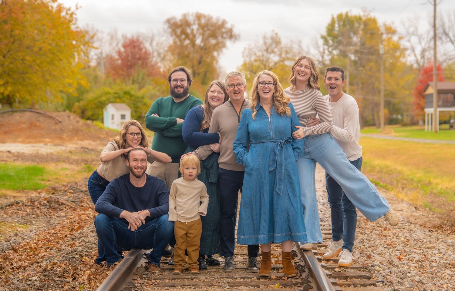 A group of people pose together outdoors during golden hour with natural lighting.