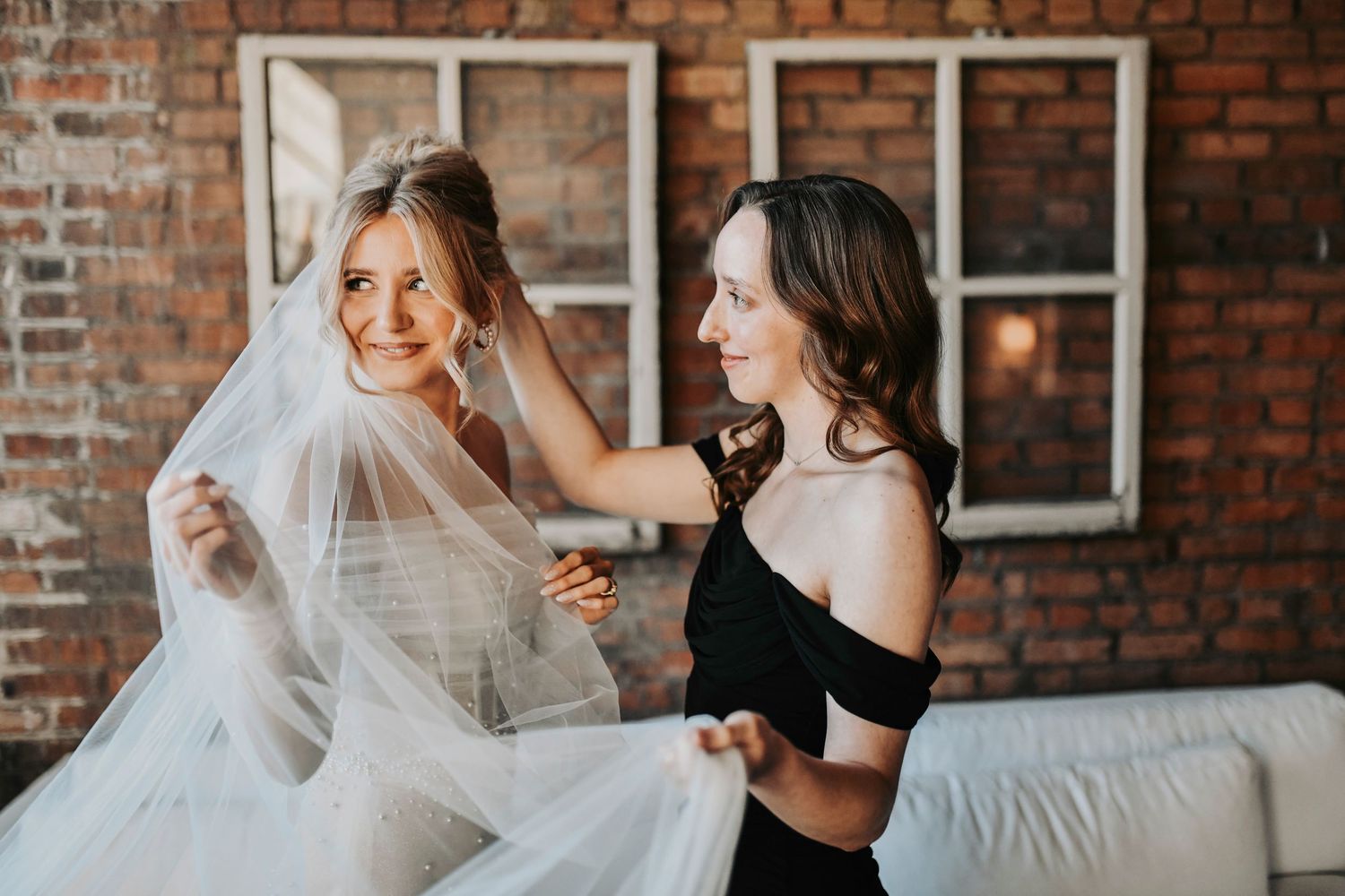 Sweet candid of the bride’s sister helping her into her dress before the Dallas wedding ceremony.