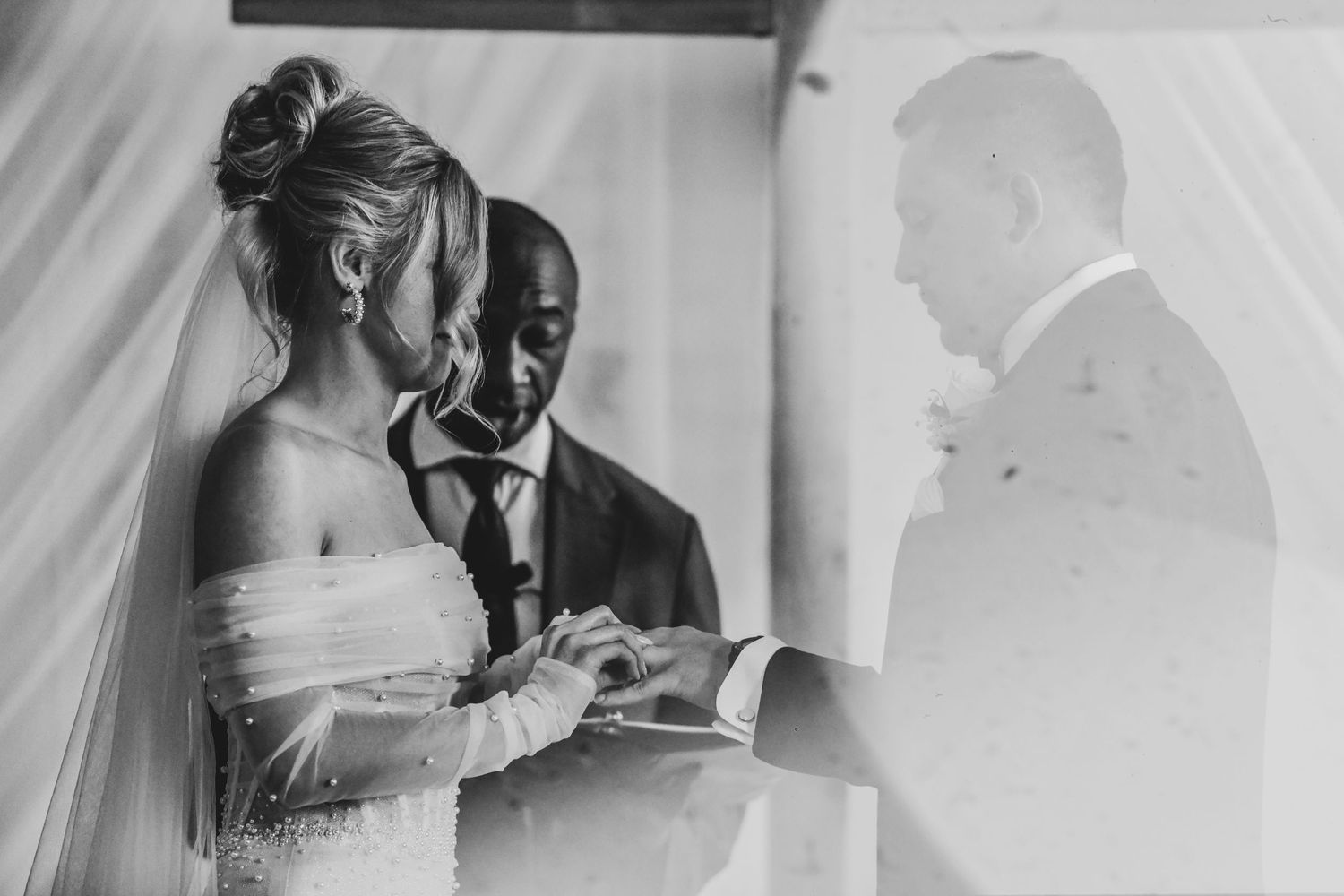 Bride and groom exchange wedding rings during their modern ceremony at Brake & Clutch Warehouse, captured in soft natural light.