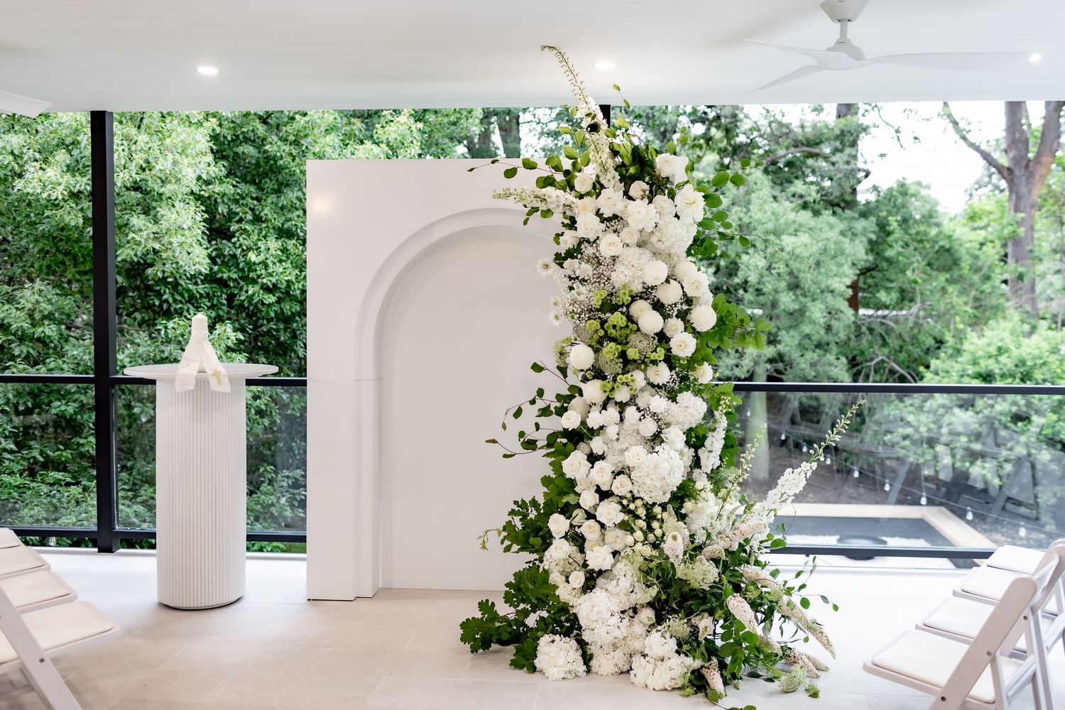 A bright and airy white interior space decorated with elegant floral arrangements and natural light streaming through windows.