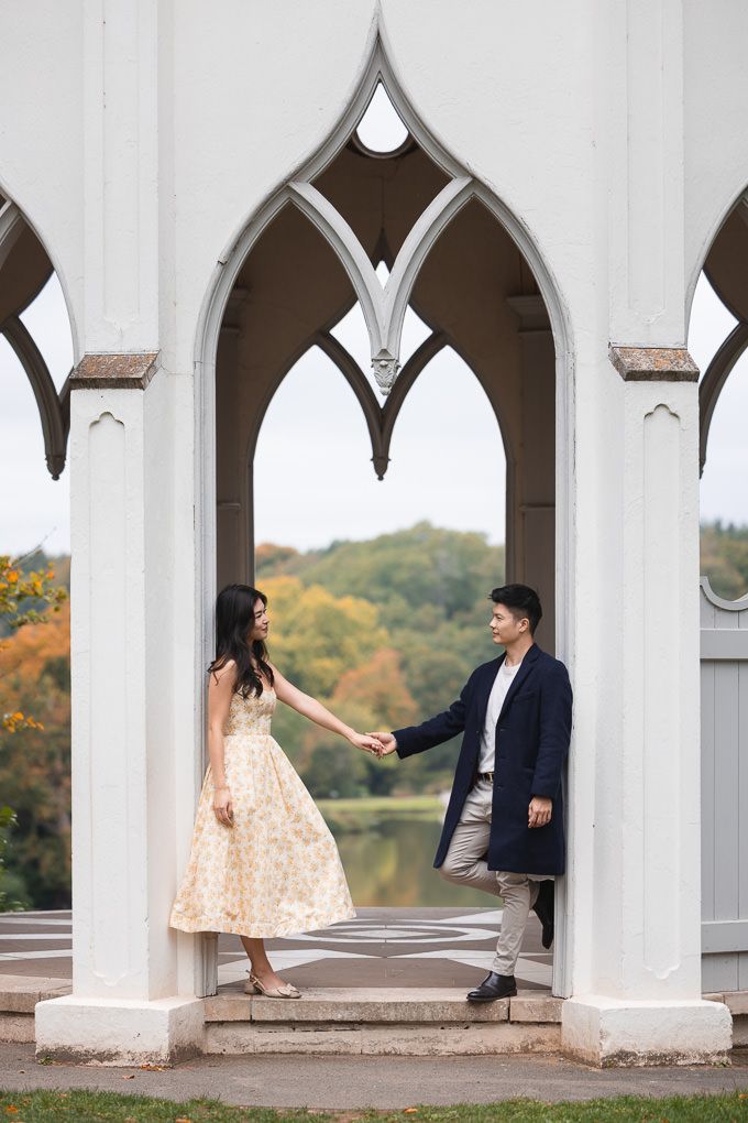 A couple in romantic poses under Gothic arches during an autumn engagement photo session at Painshill Park in Surrey.
