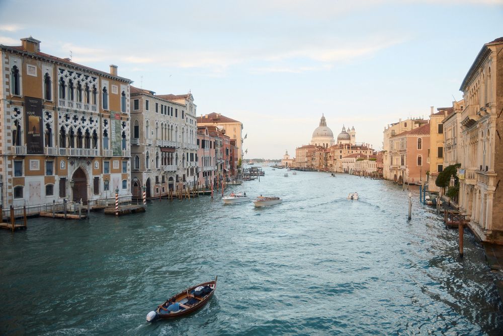 Panoramic view of Venice's Grand Canal with historic buildings and boats on turquoise water.