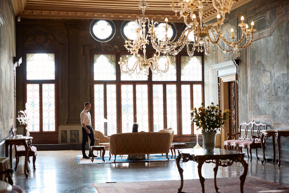 Grand ballroom with crystal chandeliers, tall windows, and antique furniture in a historic European palace.