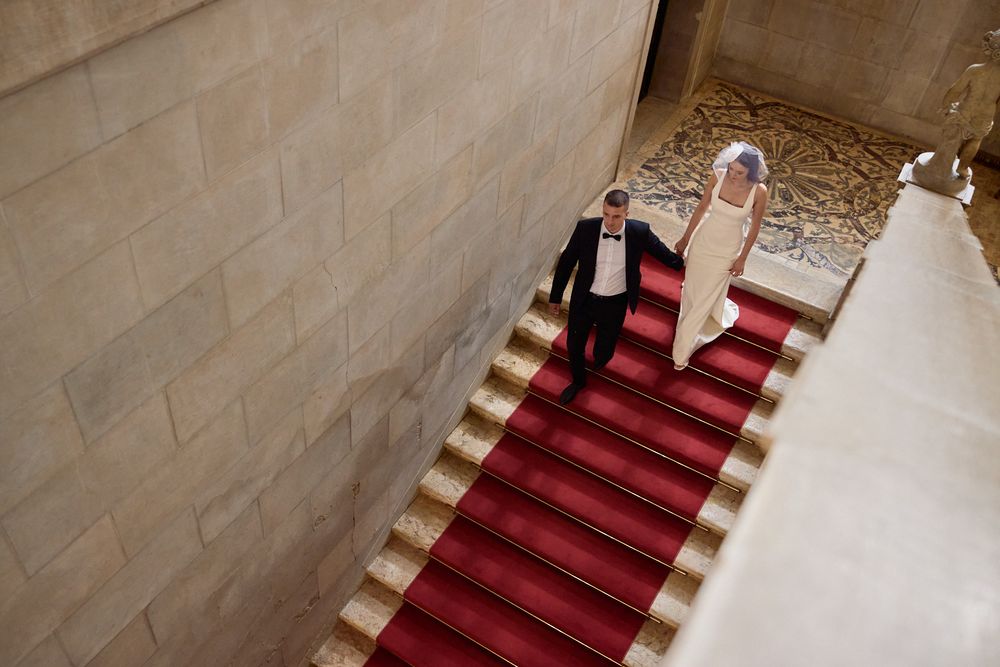 Wedding photography on grand stone staircase with red carpet.