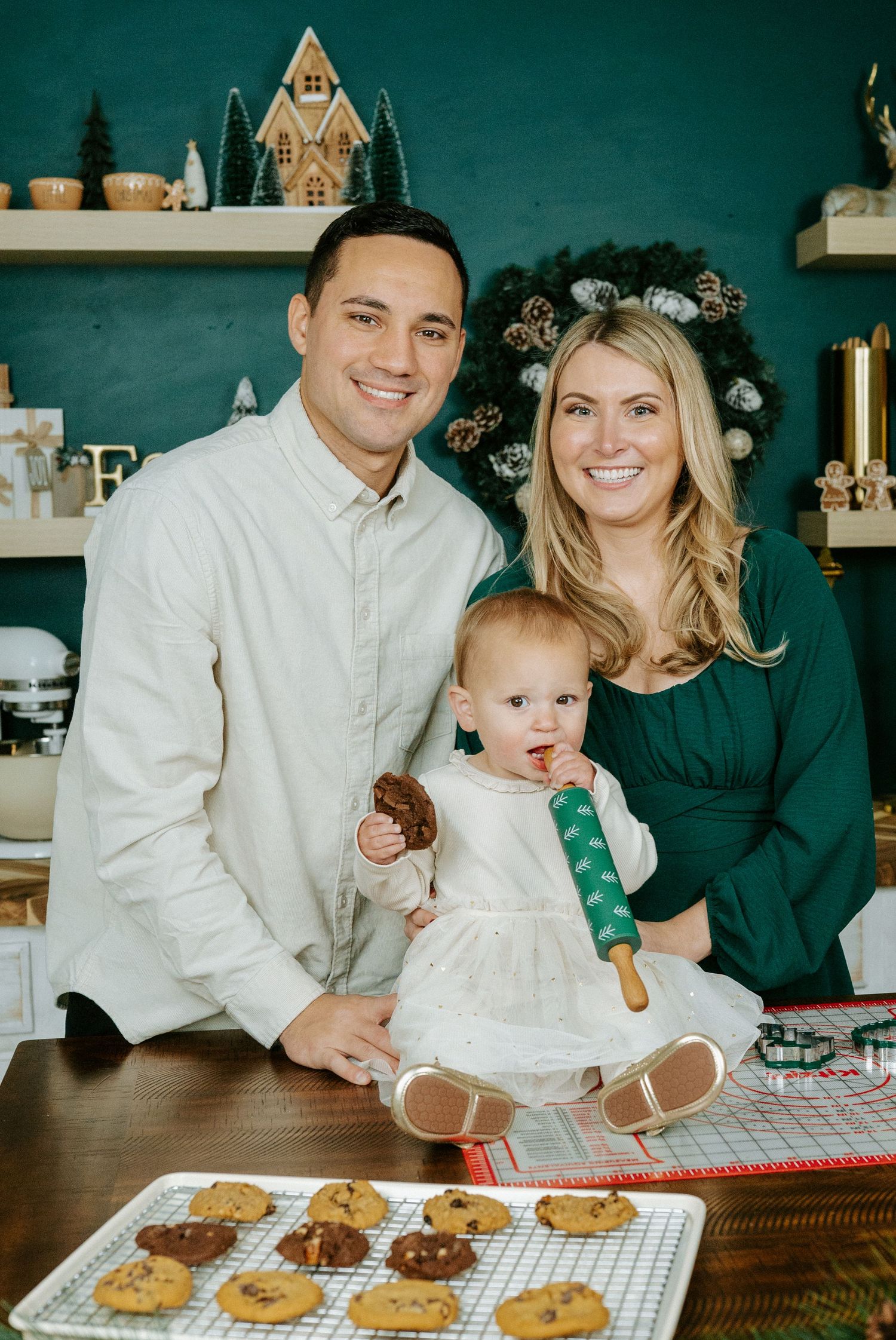 Family baking cookies together on a cooling rack with dark teal walls in the background.
