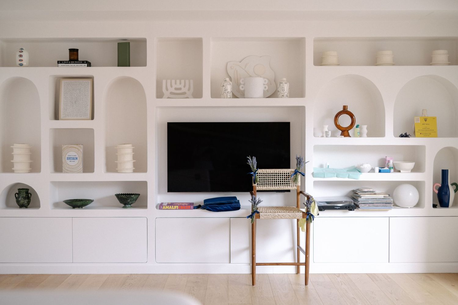 Intérieur design blanc et épuré avec étagères intégrées, décoration lumineuse et minimaliste. Chaise pour la brit mila installée.