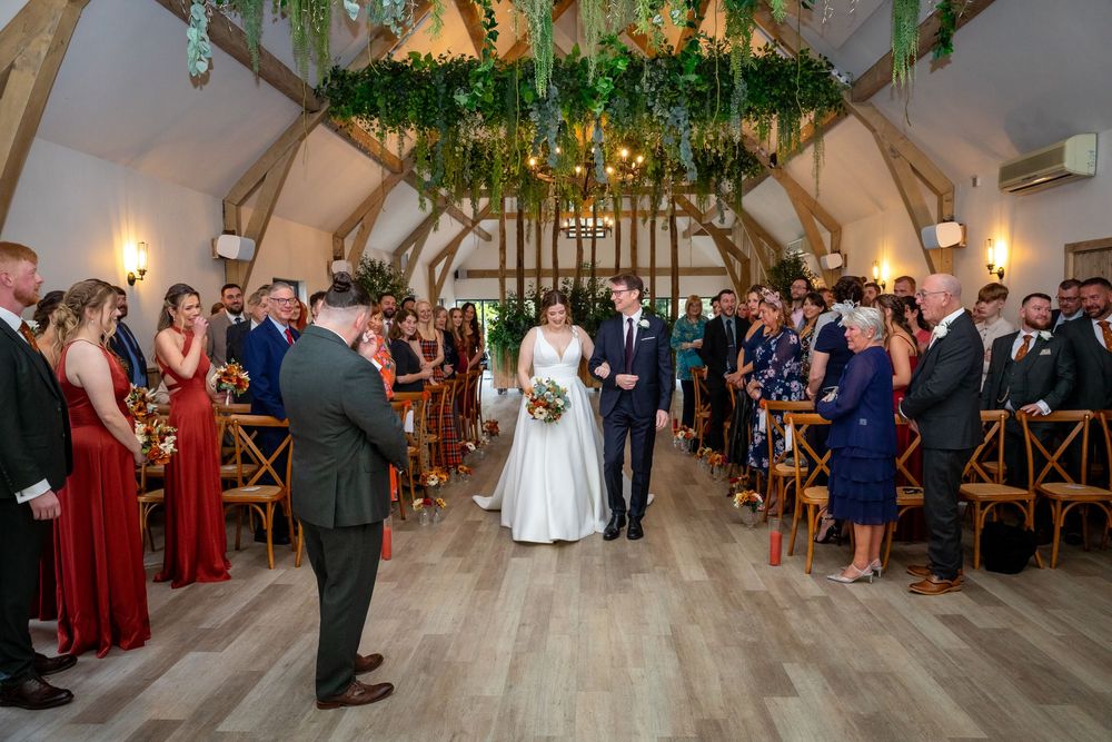 Bride and groom walk back down the aisle after their ceremony in a stunning barn wedding venue.